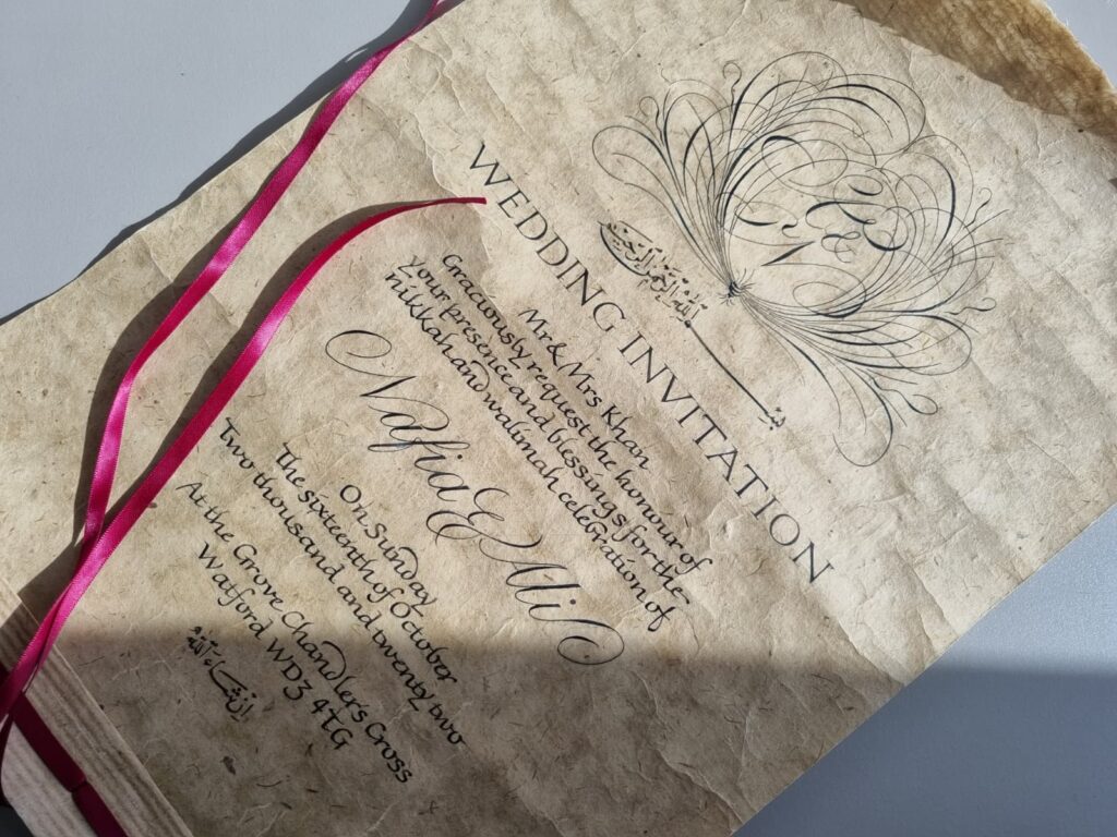 Hand lettered wedding invitation on handmade paper with a flourished monogram